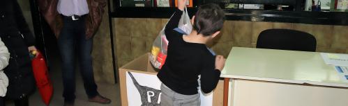 Un alumno entrega comida para gatos en el colegio Tierno Galván
