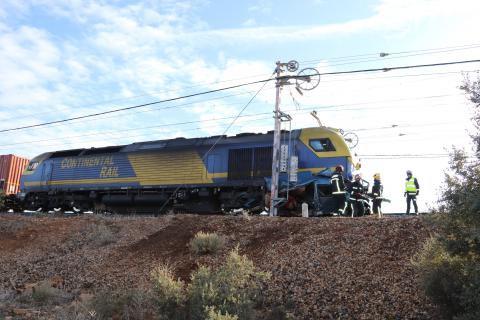 Los bomberos trabajan para extraer la furgoneta atrapada bajo la locomotora