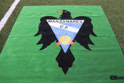 Escudo del Manzanares CF en el césped del José Camacho