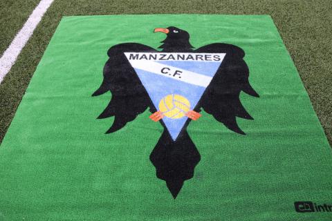 Escudo del Manzanares CF en el césped del José Camacho